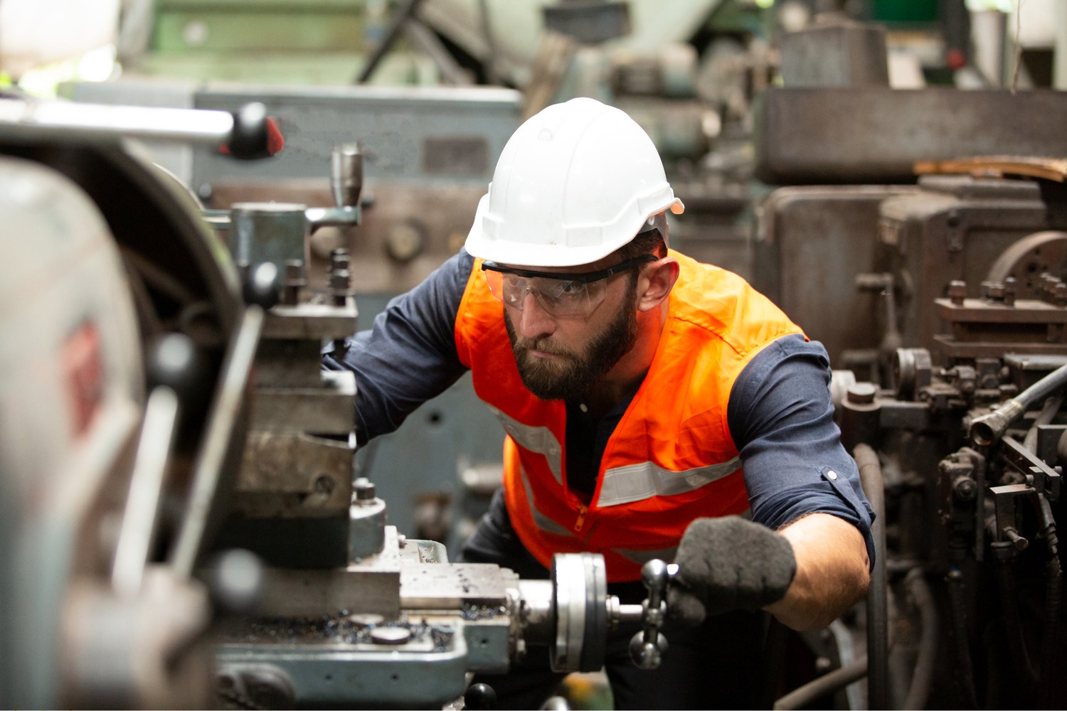 A machinist in a hard hat and safety glasses working at a lathe on an Everett shop floor