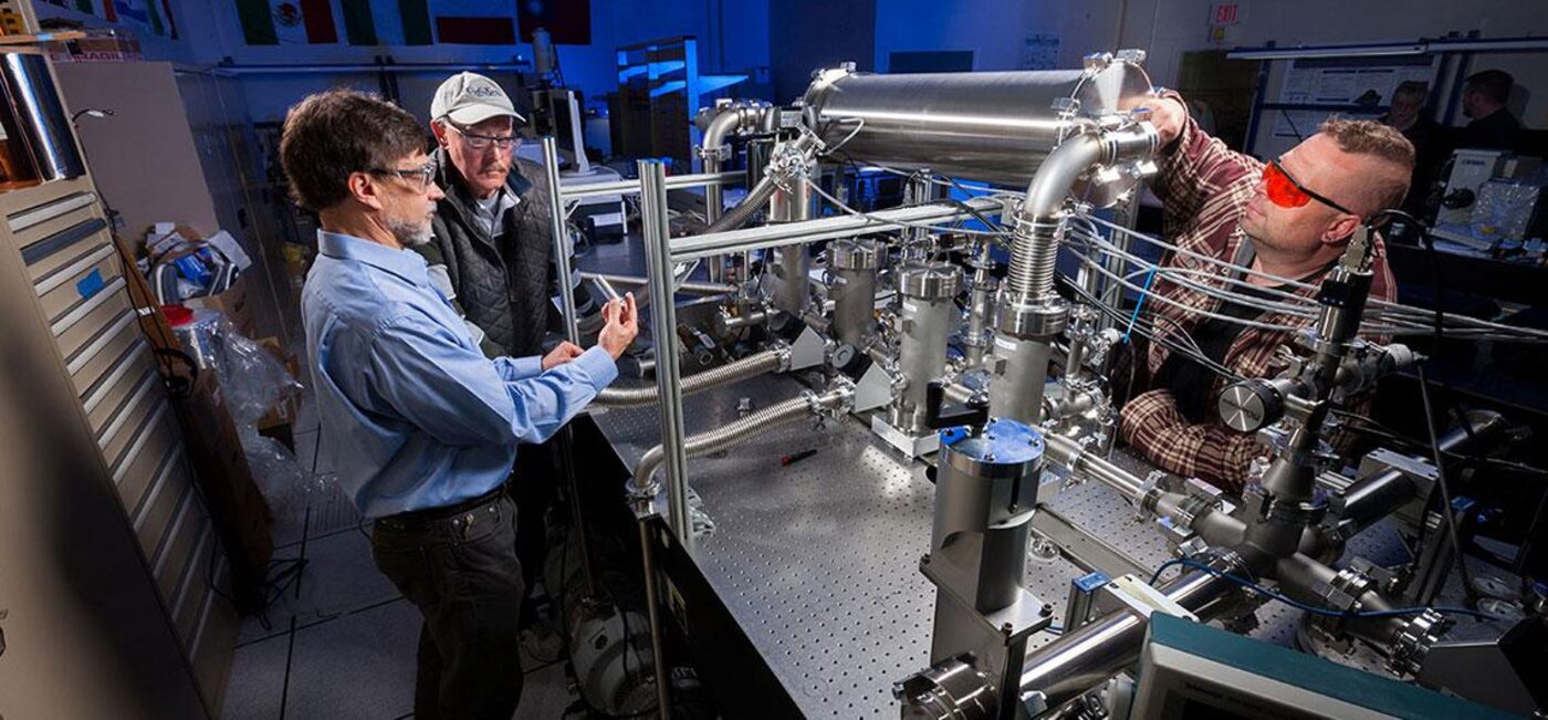 Engineers work on precision vacuum research equipment in a lab
